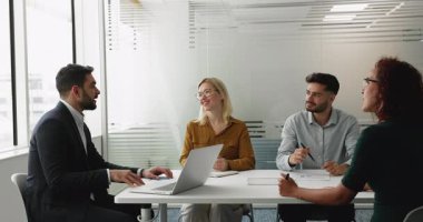 Takım elbiseli profesyonel Arap adam, yönetim kurulundaki konferans masasının etrafında oturan hissedarlarla ya da meslektaşlarıyla toplantı yapıyor. Stratejiyi, çözümü, koordinasyon ekibini paylaşıyor, ortak proje üzerinde çalışıyor.