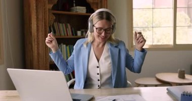 Orta yaşlı, takım elbiseli, modern kulaklıklardan müzik dinleyen, dizüstü bilgisayarı açık, dinlendirici, gitar çalan, iş arasında en sevdiği şarkıyı çalan 40 'lı yaşlarda bir iş kadını.