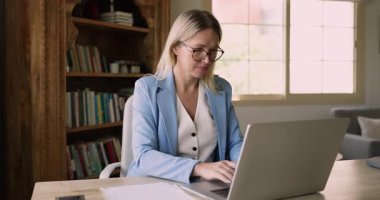 Masasında dizüstü bilgisayarla oturan, kalem tutan, burnu ve dudakları arasında kalem tutan, yaratıcı beyin fırtınalarına veya iş akışına ara veren 40 'lı yaşlarda profesyonel bir kadın.