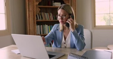 Orta yaşlı 40 'lı yaşlarda, ofis masasında oturan, bilgisayarla uğraşırken akıllı telefonla konuşan, dijital dosyaları inceleyen, uzaktan problem çözme ve müşteri danışmanlığı yapan bir iş kadını.