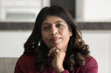 Zarif çağın güzelliği ve cazibesi. Kafa resmi sakin uzun kıvırcık saç makyajlı güzel olgun bir kadın parlak elbiseler giyer koltuğa oturur kendine güvenle kameraya bakar