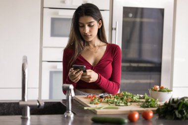 Mutfakta kaydırma molası. Sıradan bir kadın yemek tarifi detayları için telefonda arama yaparken sebze salatası hazırlamaya ara verir. Yemek pişirme videosu izleyip kalori sayma uygulaması kullanır.