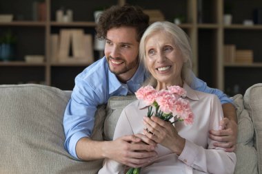 Anne tatilinde birlikte rüya görüyorduk. Sevecen yetişkin oğul, yaşlı anneye arkadan sarılıyor. Kanepeye oturmuş, kadınlar gününde sunulan çiçekleri tutuyor. Sevgi dolu anı paylaşıyor, gülümsüyor ve hayal kuruyor.