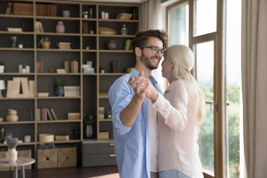 Sıcak aile anı. Sevecen milenyum adamı yetişkin bir oğul torunu modern oturma odasında yaşlı, bekar bir anneyle yavaşça dans ediyor ve sevgi dolu şükran desteği gösteriyor. Boşluğu kopyala
