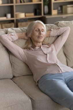 Günlük istirahatin tadını çıkarıyorum. Mutlu tembel yaşlı kadın, oturma odasındaki yumuşak rahat koltuğa uzanıyor. Hayal dünyasında, kapalı gözlerle. Stres egzersizlerini rahatlatmak için ara ver.