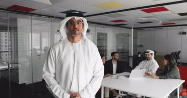 Geleneksel Orta Doğu tarzı giyinmiş gülümseyen orta yaşlı bir Arap 'ın portresi konferans odasında güven içinde duruyor ve bir grup işadamı arka planda müzakere ediyor. Toplantı, iş.