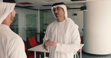 Geleneksel beyaz kanduras giymiş iki Arap adam modern yönetim kurulunda gülümsüyor, sıkı bir el sıkışma hareketi yapıyor, pazarlığa başlıyor ve başarılı bir toplantı bitiriyorlar. Anlaştık, anlaştık.