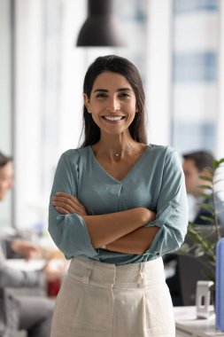 Brezilyalı iş kadınının ofis portresi, sıradan giyinmiş kameralara bakıyor, liderlik, profesyonellik ve kendine güven yayıyor, başarılardan ve kariyer büyümesinden tatmin oluyor.