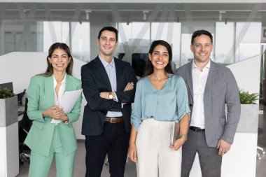 Çok uluslu dört genç takım arkadaşı, ofiste poz veren şirket çalışanları, kameraya bakın, etrafa profesyonellik saçıyor, takım çalışmasından tatmin oluyorlar. İş misyonu, liderlik, temel değerler