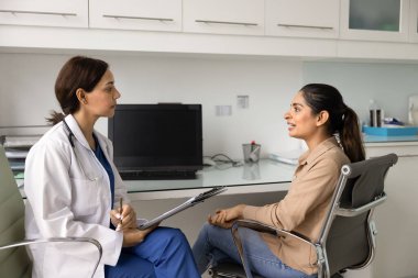 Çeşitli genç doktor ve hasta kadınlar iş yerindeki klinikte buluşuyor, doktor masasında bilgisayarın başında konuşuyor, hastalık veya bozukluk belirtilerini tartışıyor, tıbbi tavsiyeler, tedavi