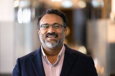 Gözlüklü yaşlı Hintli işadamının portresi, kameraya neşeli bir ifadeyle poz vermek, liderlik, otorite ve profesyonellik yayıyor. Kariyer, iş büyümesi, refah