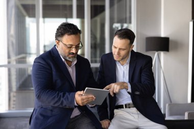 Online proje için tablet kullanan iki çok ırklı işadamı, beyin fırtınası fikirleri, finansal tahminleri kontrol etmek, takım performans verilerini değerlendirmek, şirket stratejisini planlamak, iş planı üzerinde işbirliği yapmak