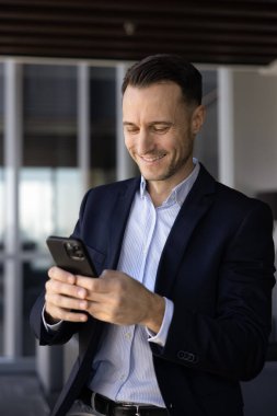 Ofisteki akıllı telefonunu kullanarak resmi giyinen bir işadamı, gelen mesaja cevap verir, iş arkadaşıyla dijital iletişimde yol gösterir, mesajlaşır, kişisel ve keyifli bir konuşma yapar, uygulamayı kullanır.