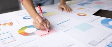 Stratejik planlama, veri odaklı karar verme. Kadınların eli yapışkan notlara yakın, konferans masasında mali tablolar, analitik raporlar ve grafiklerle çalışıyor.