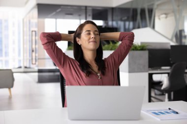 Pozitif profesyonel kadın çalışanlar rahat bir ofis koltuğunda otururken elleri kapalı, gözleri kapalı, gülümseyen, iş sonuçlarından zevk alan ve duraklayan bir şekilde dinlenirler.