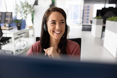 Gülen kadın, çağrı merkezi operatörü kablosuz kulaklık takıyor, müşteriyle konuşuyor, profesyonel yardım sağlıyor, modern ortak çalışma alanında bilgisayarla masaya oturan danışman müşteri,