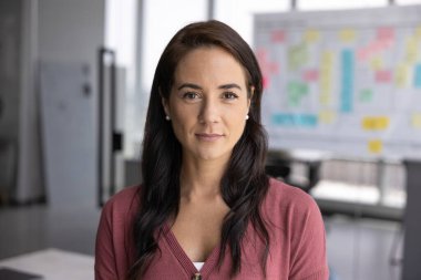 Çekici iş kadını, ofis çalışanı kameraya bakıyor, çalışma alanında poz veriyor, güven, liderlik ve profesyonellik yayıyor. Başarılı girişimci, proje yöneticisi, kafa portresini kapatın