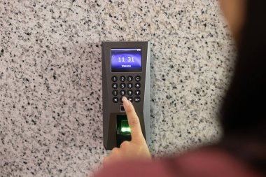 Tanımlanamayan bir kadının ofis odasına girdiği, şifreye bastığı, anahtarsız erişim akıllı sistemini kullandığı yakın plan görüntüsü. Güvenli iş yeri erişim denetimi ve dijital kimlik doğrulama, doğrulama