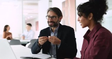 Pozitif Latin iş adamı genç Hintli profesyonel iş arkadaşı, müvekkil, tavsiye ve danışmanlık ile konuşuyor. Çalışma alanındaki çalışma masasında çeşitli meslektaşlar konuşuyor