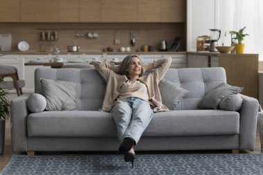 Mutlu rüya gibi, sakin, gri saçlı kadın rahat koltukta dinleniyor, tembelce hafta sonunun tadını çıkarıyor, modern, rahat evde boş boş vakit geçiriyor, serin havayı soluyor, uzaklara bakıyor, düşünüyor, hayal kuruyor.