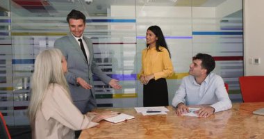 Team members sit at conference desk, applauding to newcomer, best employee of month, congratulate young Indian woman colleague with professional success, reward or promotion during meeting led by boss