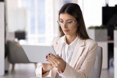 Ofisteki dijital tablet bilgisayarda yazan gözlüklü genç Latin CEO kadın, iş için internet çözeltisi, çevrimiçi ürün, web servisi, etkili şirket yönetimi uygulaması