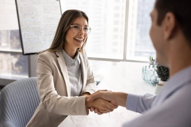 Genç ve mutlu Latin iş kadını erkek iş ortağıyla toplantıda tokalaşıyor, mülakat üstüne iş adayı kiralıyor, çalışana iyi bir iş için saygı gösteriyor, gülümsüyor, gülüyor.