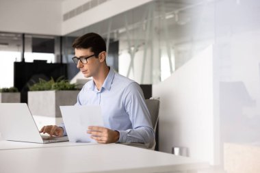 Ofis masasında evrak üzerinde çalışan, dizüstü bilgisayarda yazı yazan, kağıt rapor hazırlayan ciddi bir İspanyol uzmanı. Genç işadamı iş yerinde evrak işleriyle uğraşıyor.