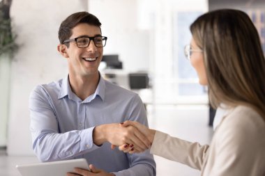 Gözlüklü başarılı Latin iş adamı mali hukuk uzmanına yardımları için teşekkür ediyor, kadın meslektaşının elini sıkıyor, müzakere toplantısını bitiriyor, anlaşma yapıyor, gülümsüyor.