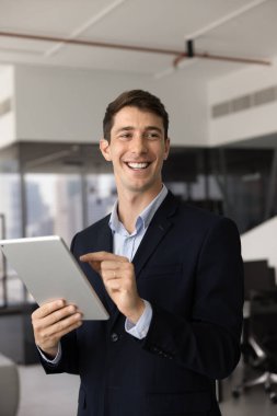 Dijital tablete yazı yazan mutlu, genç İspanyol işadamı, alet edevat, ticaret, profesyonel iletişim, başka yere bakmak, gülümsemek, gülmek için finansal servisi kullanıyor. Gizli dikey çekim