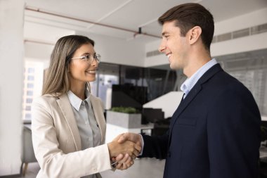 İki mutlu erkek ve kadın iş ortağı tokalaşmayı bitiriyor, gülümsüyor ve ofiste duruyorlar. İş adamı, danışmanlık, hukuki ve mali yardım için kadın uzmana teşekkür ediyor