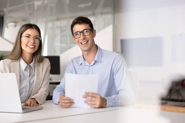 Ofis masasında birlikte çalışan iki genç Latin iş uzmanı, takım çalışması, analiz, işbirliği, fotoğraf çekimi için gülümseyen kağıt hukuki belgeler ve dizüstü bilgisayar kullanıyorlar.