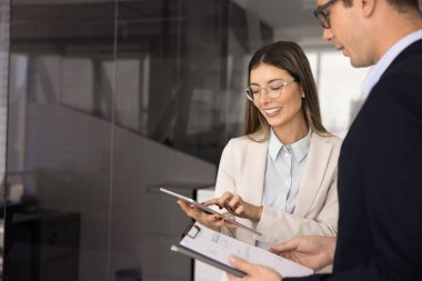 Birkaç iş arkadaşı raporları kontrol ediyor, not panosu ve tablet bilgisayarına danışıyor, proje analizleri üzerinde birlikte çalışıyor, konuşuyor, gülümsüyor. Kopyalama alanı ile gizli çekim