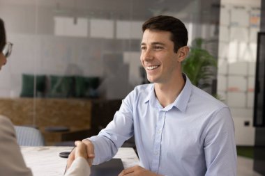 Neşeli Latin profesyonel erkek danışmana, iş ortağına, iş arkadaşına toplantı masasında el sıkışırken desteğe, danışmaya, gülümsemeye saygı duyduğunu söylüyor.