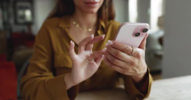 Cropped shot of young woman typing on mobile phone at home, using web service for online communication, making order on Internet, browsing social media, managing e-business project