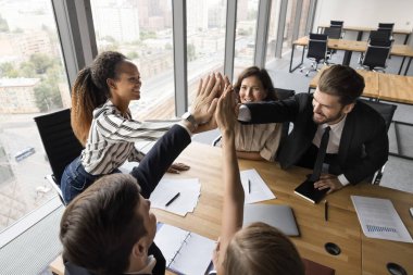 Sinerji ve takım ruhu. Mutlu çok kültürlü ofis çalışanları grup toplantısında takım oluşturma faaliyetinde bulunan girişimciler aktif genç bayan liderle beşlik çaktı.