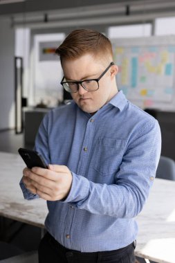 İnternet teknolojisini kullanarak Down sendromlu erkek çalışana odaklanmak, şirket ofisindeki cep telefonunda online uygulama, cep telefonuna yazmak, sosyal medyada gezinmek.
