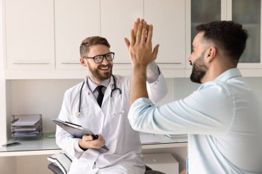 Mutlu doktor ve hasta beşlik çakıyor, başarı jesti, etkili tedavi planı, hastanede tıbbi danışmanlık yapıyor. Dostça etkileşim, güven, profesyonel sağlık hizmetleri