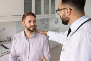 Erkek terapist ya da kardiyolog elini erkek hastanın omzuna koyar, ileriki ameliyatlar, tedavi planı ya da teşhisi, güven vermesi, profesyonel sağlık hizmetleri danışmanlığı