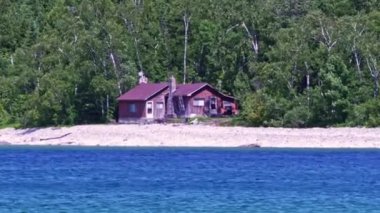 Cottages at limestone rocky cliff with green forest by Lake Huron Lion's Head Beach Harbour in Lion's Head Provincial Park Ontario Canada. Isthmus Bay, Lion's Head Point. Houses for seasonal vacation