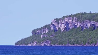 Amazing clean fresh water and green spruce forest on rocks at Lion's Head Beach Harbour in Lion's Head Provincial Park Ontario Canada. Isthmus Bay lake Huron. Great place for vacation tourist visit.