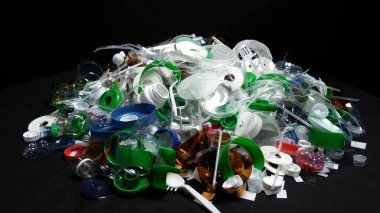 Plastik şişe parçaları, bardaklar, mantarlar, pipetler, su ve şampuan şişeleri, krem ambalajlar ve masaya atılan diğer bir kerelik çöpler. Çevre kirliliği, geri dönüşüm, atık yönetimi sorunu.