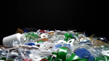 Tek kullanımlık plastik çöp. Geri dönüşümsüz plastik atıkla çöp sahalarının aşırı kirlenmesine dikkat çekmek. Masanın üzerinde biyolojik olarak çözünemeyen zehirli bir çöp var. Çevre sorunları.