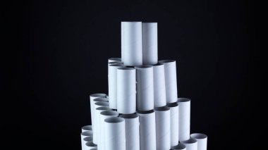 Siyah arka planda boş tuvalet kağıdı ruloları. Hijyen malzemeleri piramidi, Covid-19 koronavirüs salgını sırasında tükenmiş tuvalet eşyaları. Karantina ve kendini izole etme alanındaki boş stoklar.