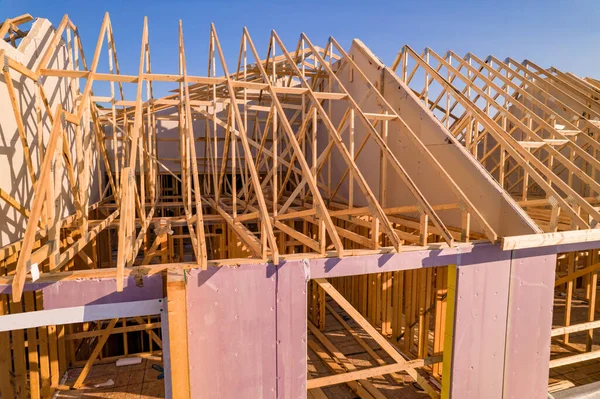 Roofing construction aerial. Wooden roof frame installation of the house. Truss beams structures on new home view from above. Golden hour. House or family home construction and real estate.
