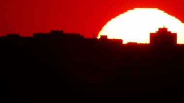 Sinema güneşi kırmızı sarı ve turuncu gökyüzünde batıyor. Sıcak yaz atmosferi sıcak hava dalgasında. Sarı güneş destansı altın saat hızında batıyor. Büyük yuvarlak güneş diskini kapat.