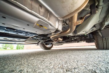 Otomotiv teknisyeninin aşağıdan görüntüsü. Otomobil egzoz sistemi ve hortumlar. Tüm teker çekişli trans dingil ve tekerlek süspansiyonlu benzin deposu. Garaj hizmetleri, araba tamiri, yol servisi..