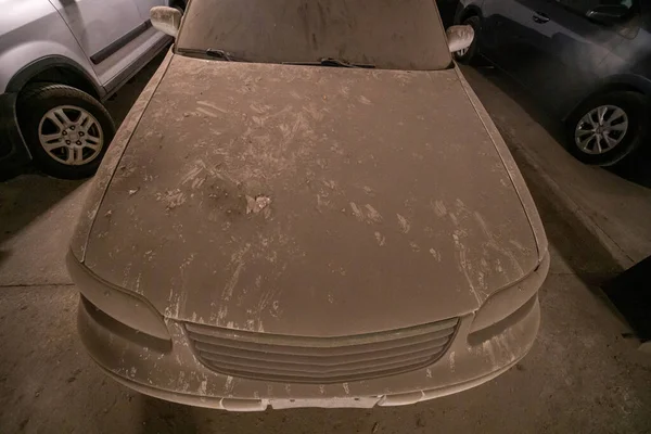 Entirely dirty car front view. Vehicle windshield glass, side mirrors, doors, hood, and windows in dust and dirt. Disgusting dirty car in filth, rodent like rats or squirrels paws prints all over it.