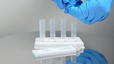 Mavi eldivenli erkek hemşireye yakın çekim tampon tüplerine test reaktörleri bırakıyor. Burnundan alınan örneklerde Covid 19 hayati antijenin nitel tespiti. Kendini test etmek için..