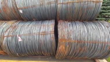 Stowage of metal wire rods in coils near manufacturing. Bundle of industrial metal wire coils ready for processing. View of made steel billets urban area of steel factory manufacturing.